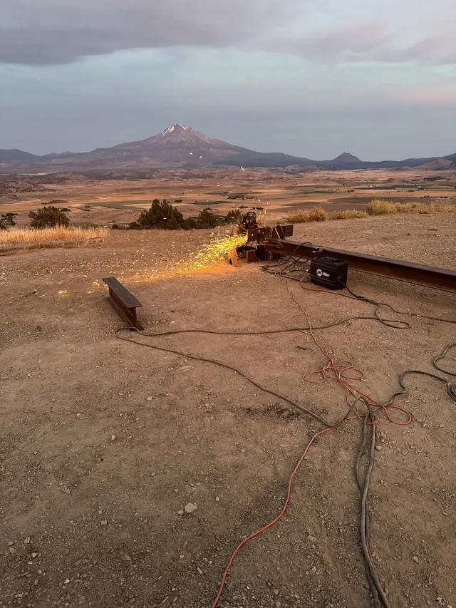 Sparks from grinding steel on a hilltop job site above the Shasta Valley at dusk
