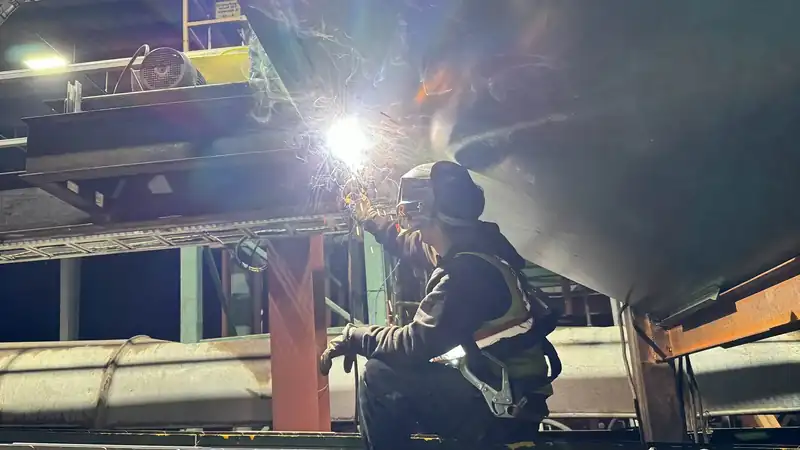 AHT welder welding heavy steel at night with the arc lighting the work