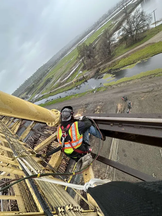 Welder clipped in on heavy industrial steel at height