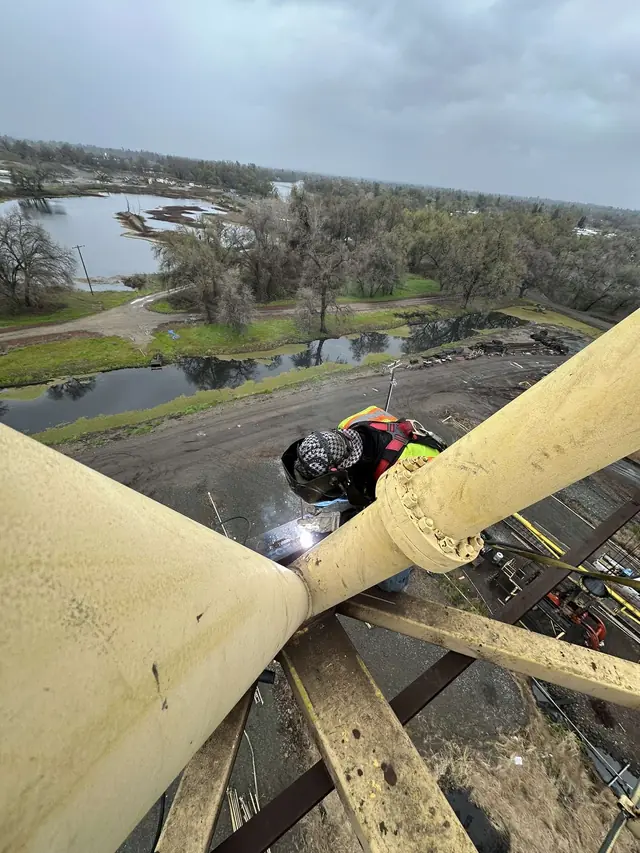 Welder in fall protection welding on heavy industrial steel at height
