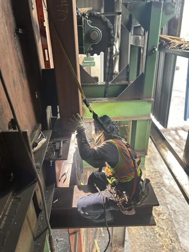 Welder repairing heavy machinery inside an industrial plant