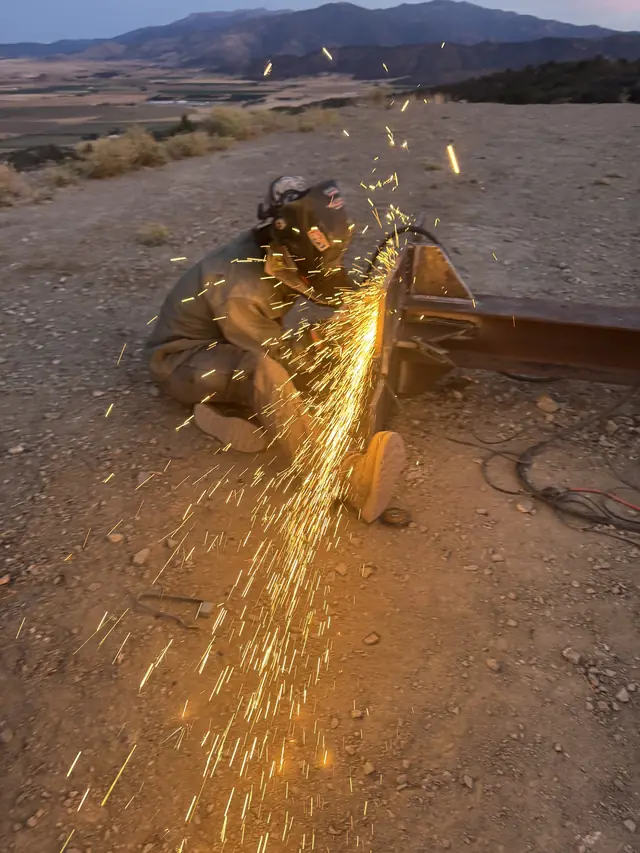 Grinding heavy steel with sparks flying on a Montague job site at dusk