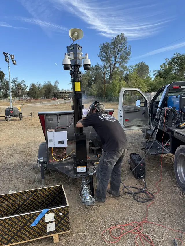 AHT welder bent over a trailer repair in a Redding equipment yard, service truck alongside
